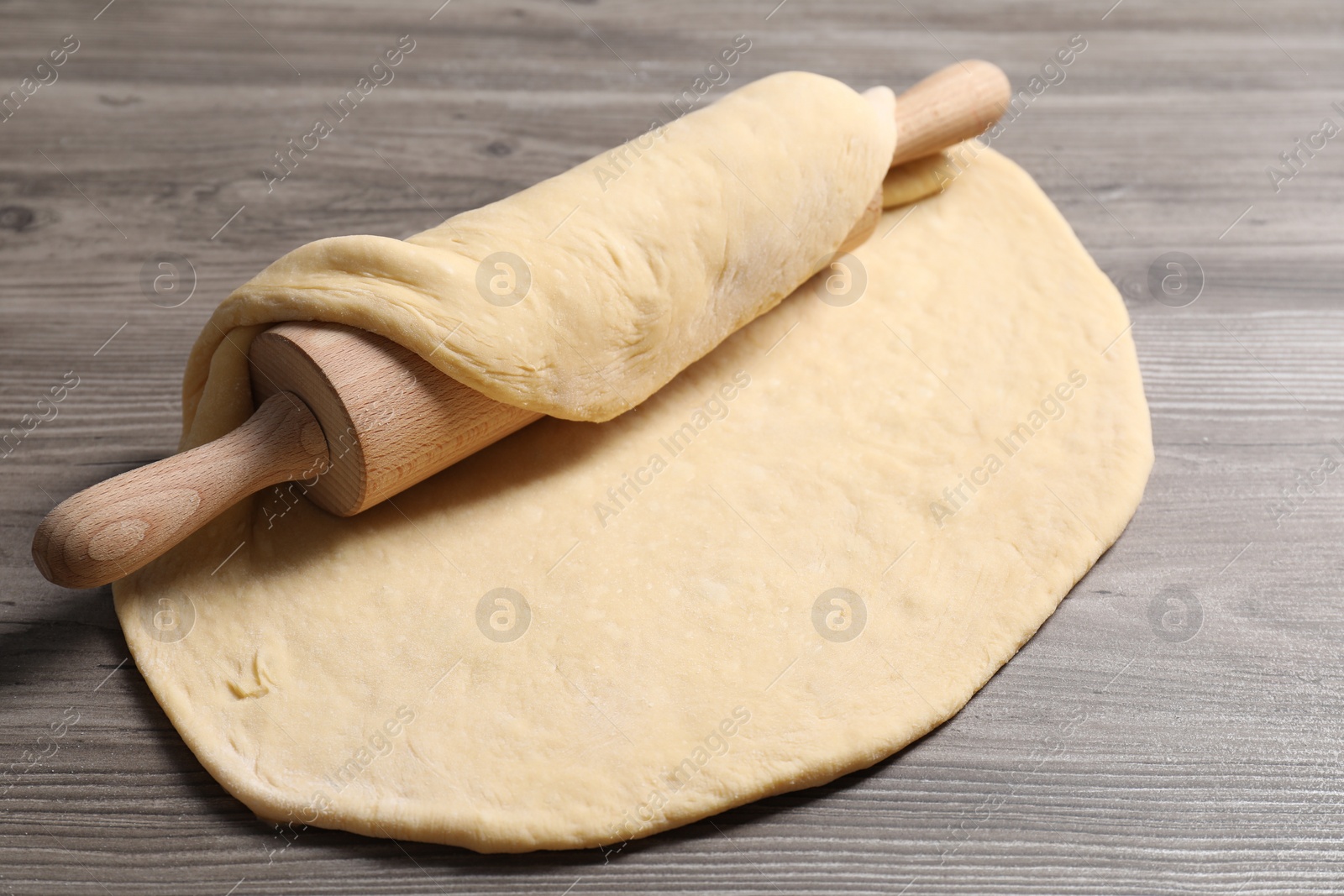 Photo of Raw dough and rolling pin on wooden table