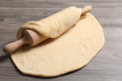 Photo of Raw dough and rolling pin on wooden table