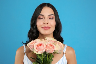 Photo of Young woman with beautiful bouquet on light blue background