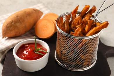Sweet potato fries and ketchup on wooden board, closeup