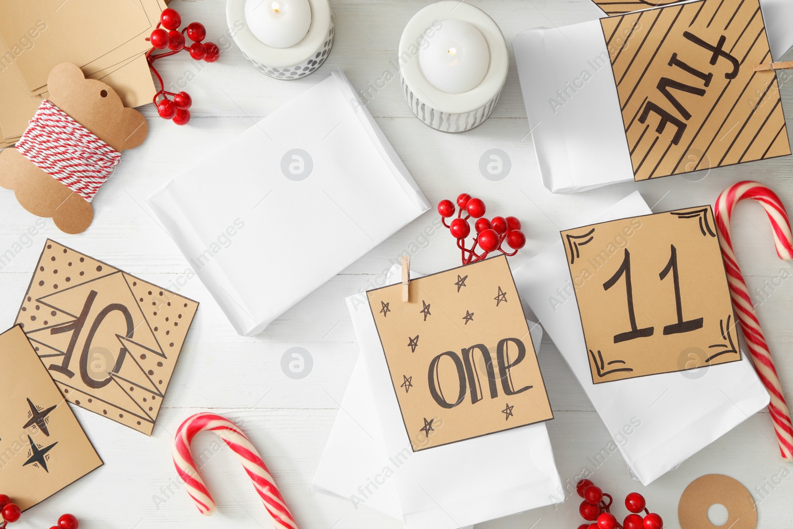 Photo of Flat lay composition with gift bags on white wooden table. Creating advent calendar