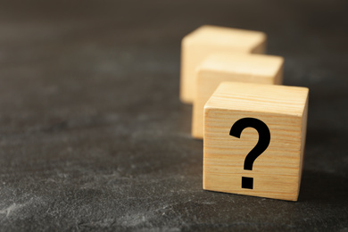 Photo of Cube with question mark on grey stone table, closeup. Space for text