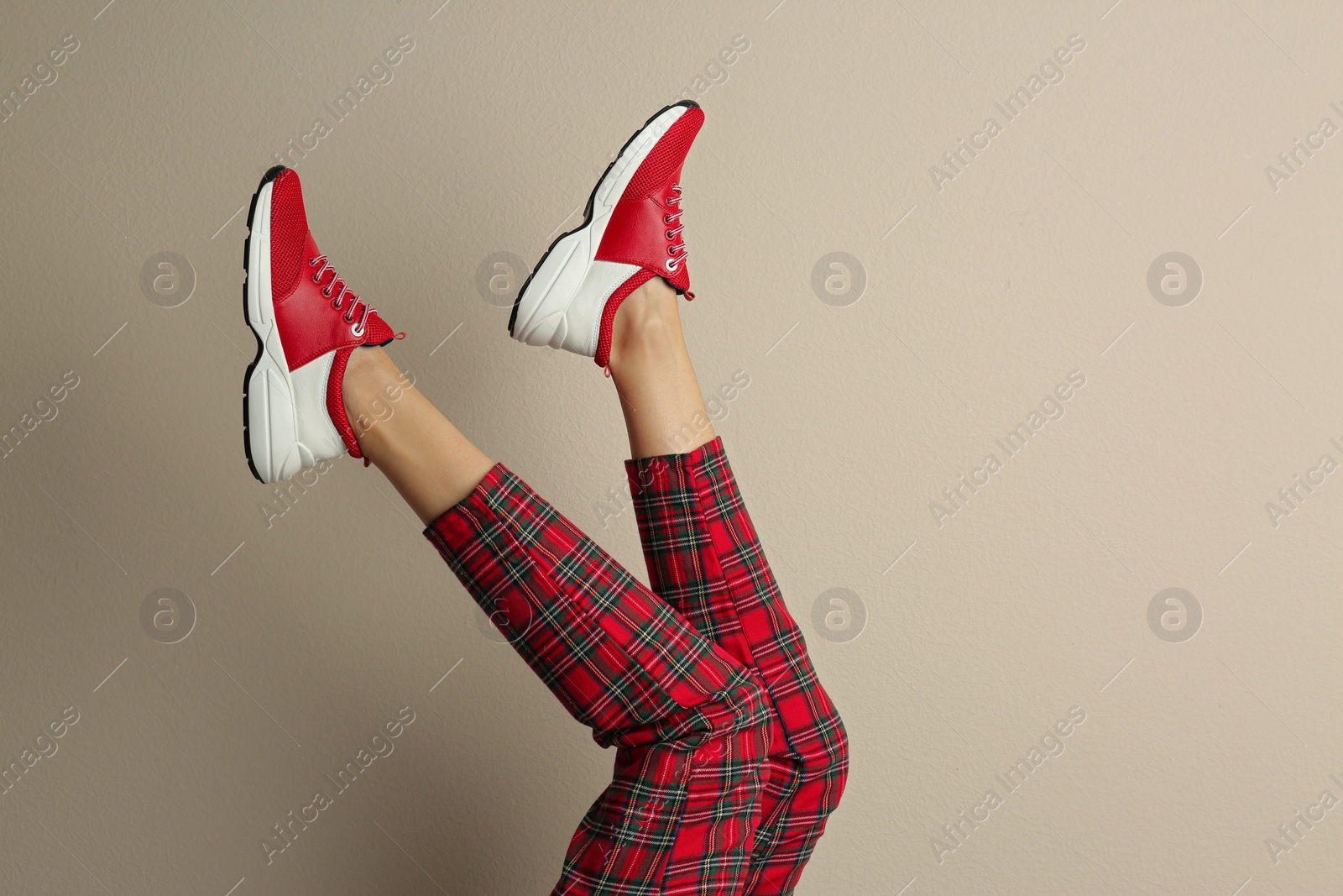 Photo of Woman wearing sneakers on beige background, closeup