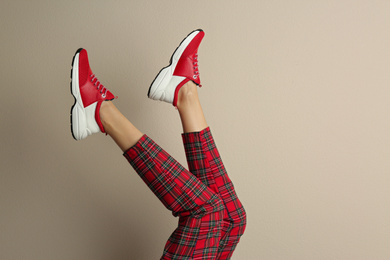 Woman wearing sneakers on beige background, closeup