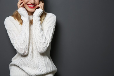 Photo of Beautiful young woman in warm sweater on dark background. Space for text