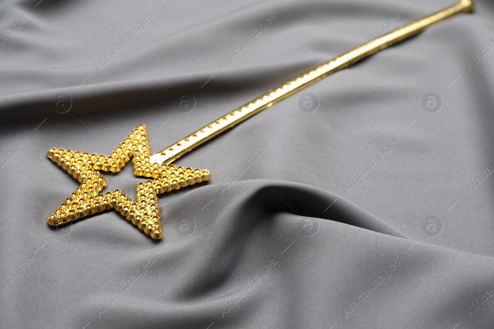 Photo of Beautiful golden magic wand on grey fabric