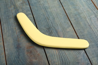 Photo of Yellow boomerang on light blue wooden background. Outdoors activity