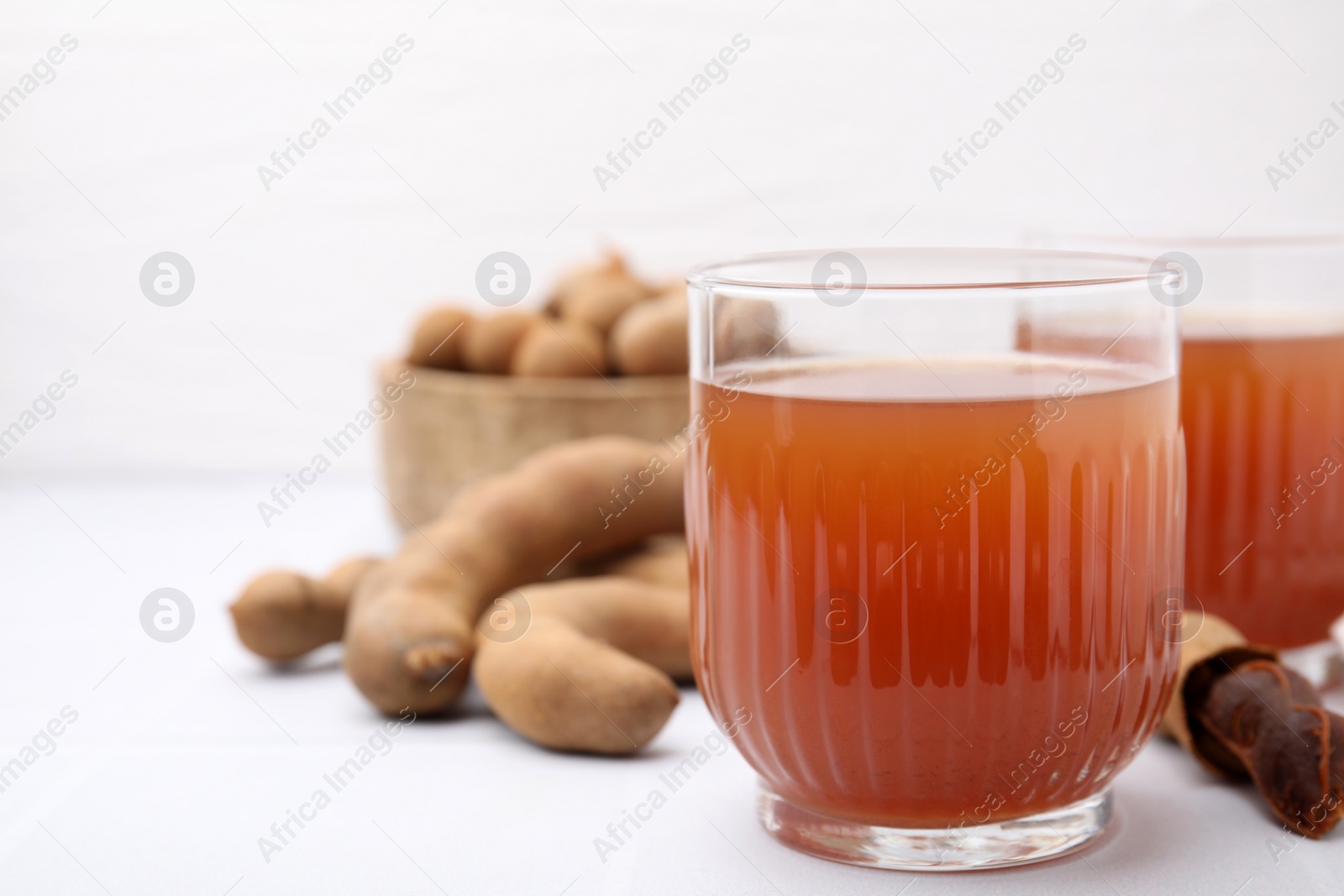 Photo of Tamarind juice and fresh fruits on white table, closeup. Space for text