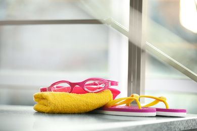 Photo of Swimming cap, goggles, flip flops and towel against blurred background. Space for text