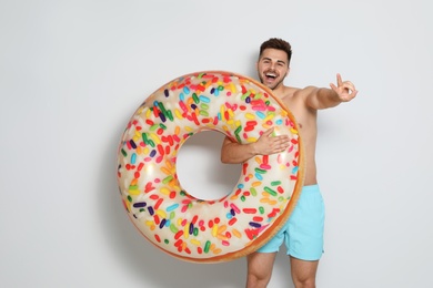 Photo of Handsome young man with bright inflatable ring on light background
