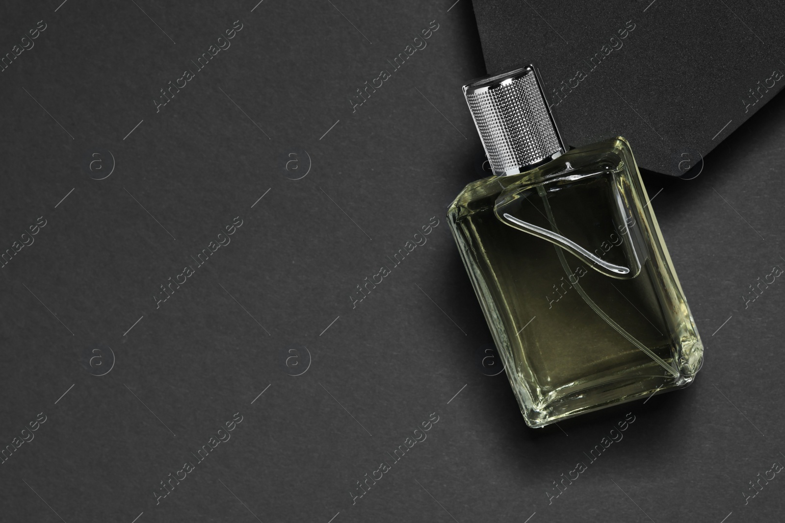 Photo of Stylish presentation of luxury men`s perfume in bottle on black background, top view. Space for text