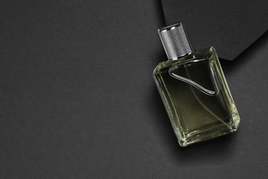 Photo of Stylish presentation of luxury men`s perfume in bottle on black background, top view. Space for text