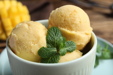 Photo of Delicious mango ice cream in bowl on table, closeup