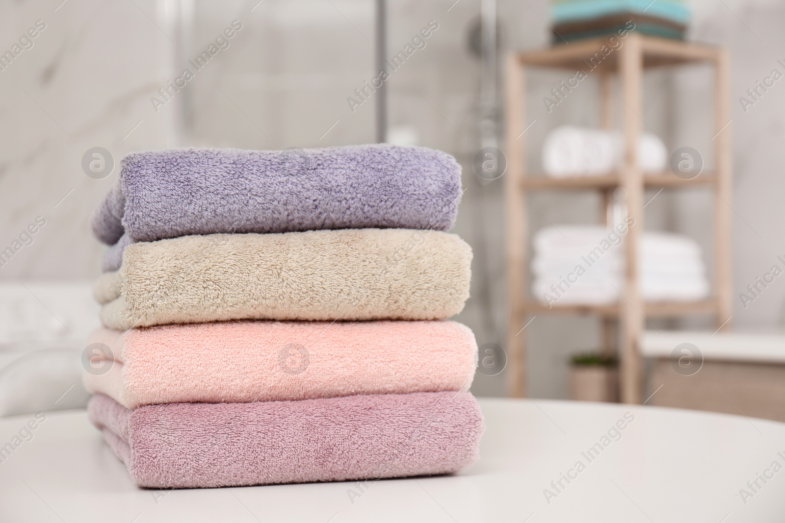 Photo of Stack of color towels on white table in bathroom, closeup