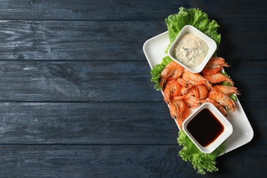 Photo of Plate with juicy shrimps and sauces on table, top view