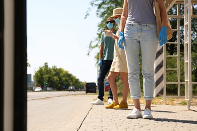 Photo of People keeping social distance in line at bus stop. Coronavirus pandemic