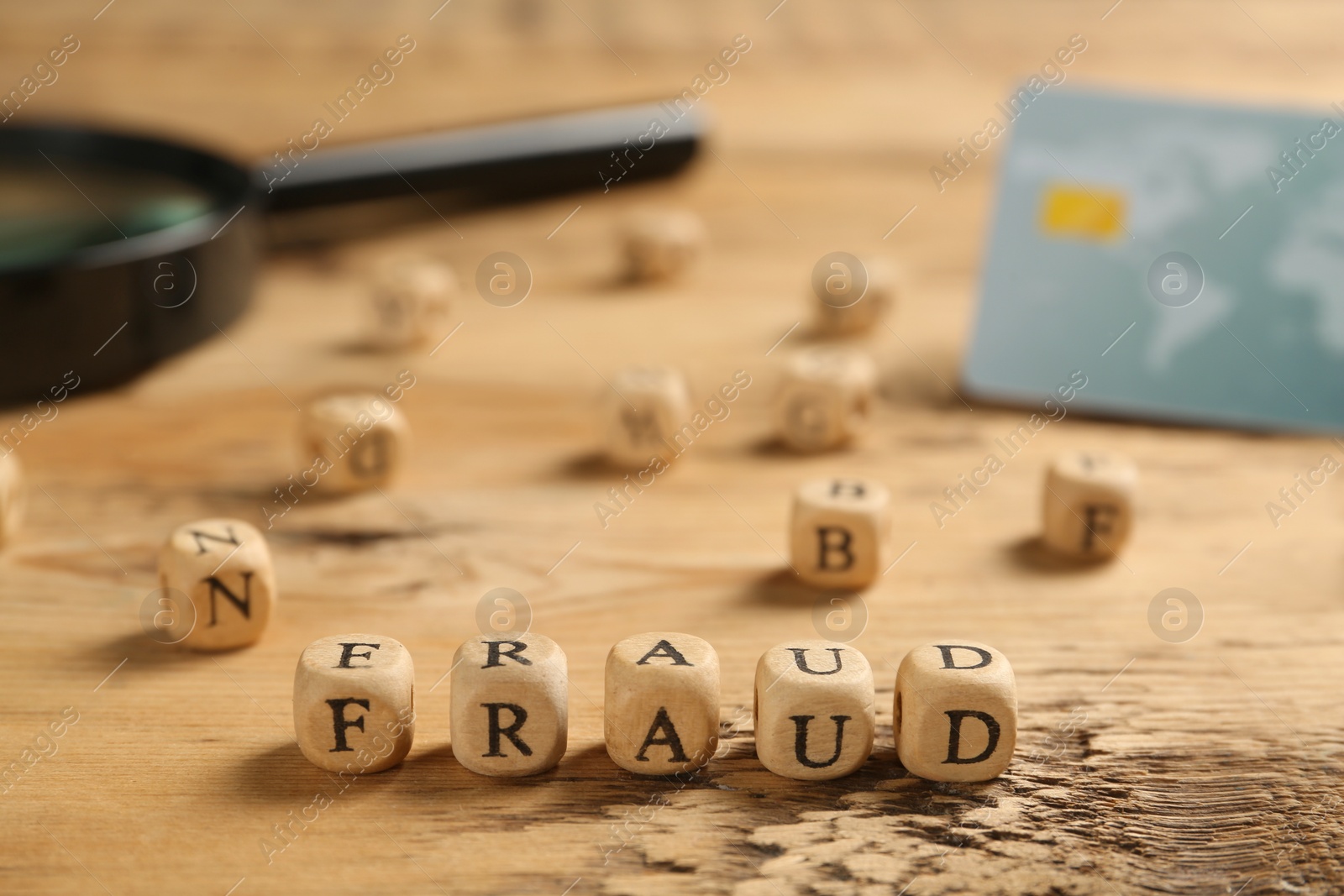 Photo of Word Fraud of cubes with letters on wooden background. Space for text