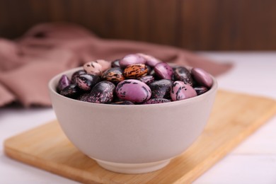 Photo of Bowl with dry kidney beans on white table, closeup