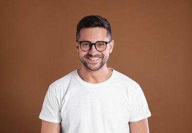 Photo of Portrait of happy man in stylish glasses on brown background