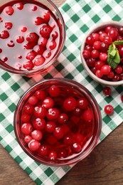 Photo of Tasty cranberry juice in glasses and fresh berries on wooden table, flat lay