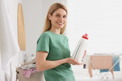 Beautiful woman holding fabric softener in bathroom