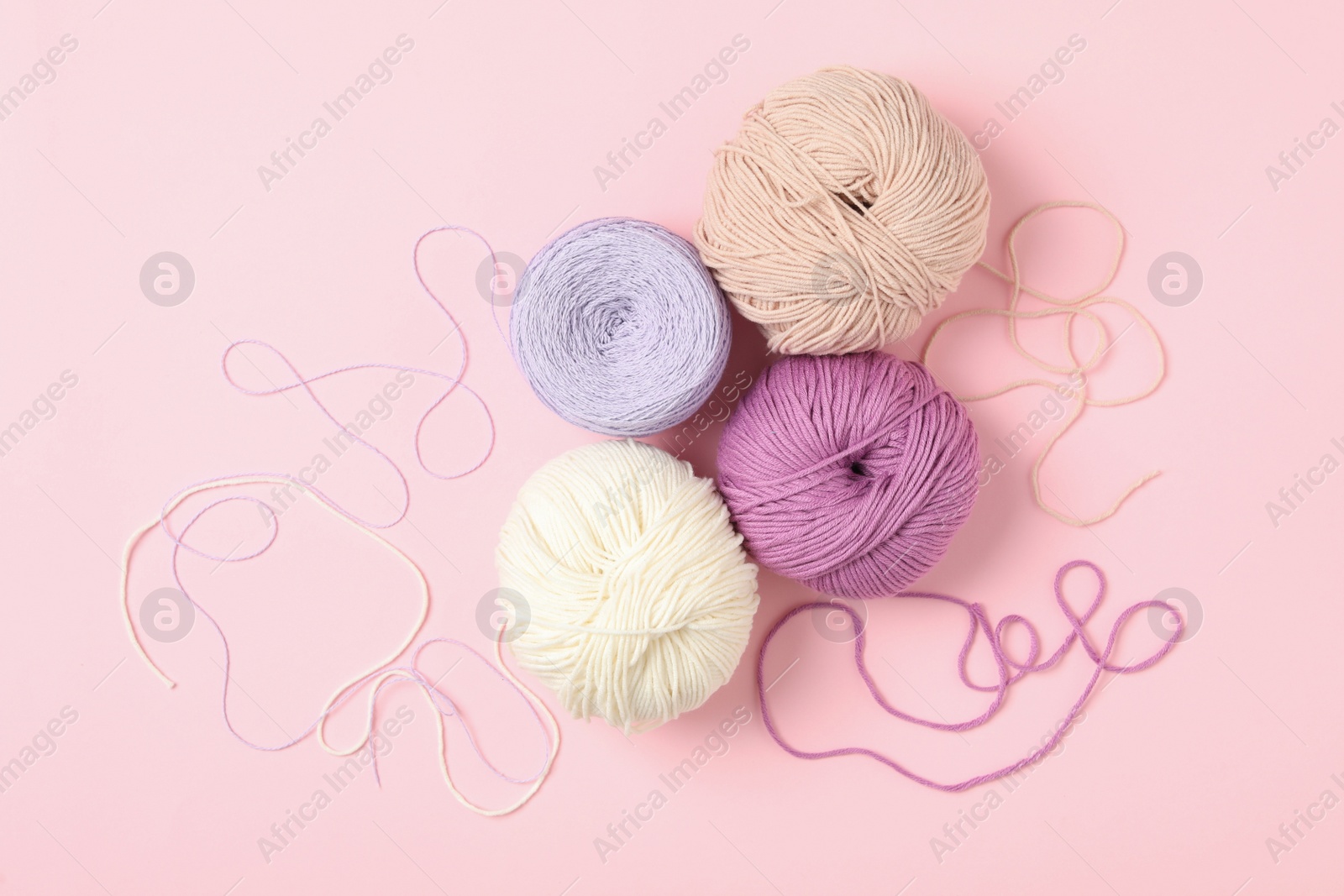 Photo of Soft woolen yarns on pink background, flat lay