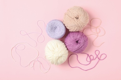 Photo of Soft woolen yarns on pink background, flat lay