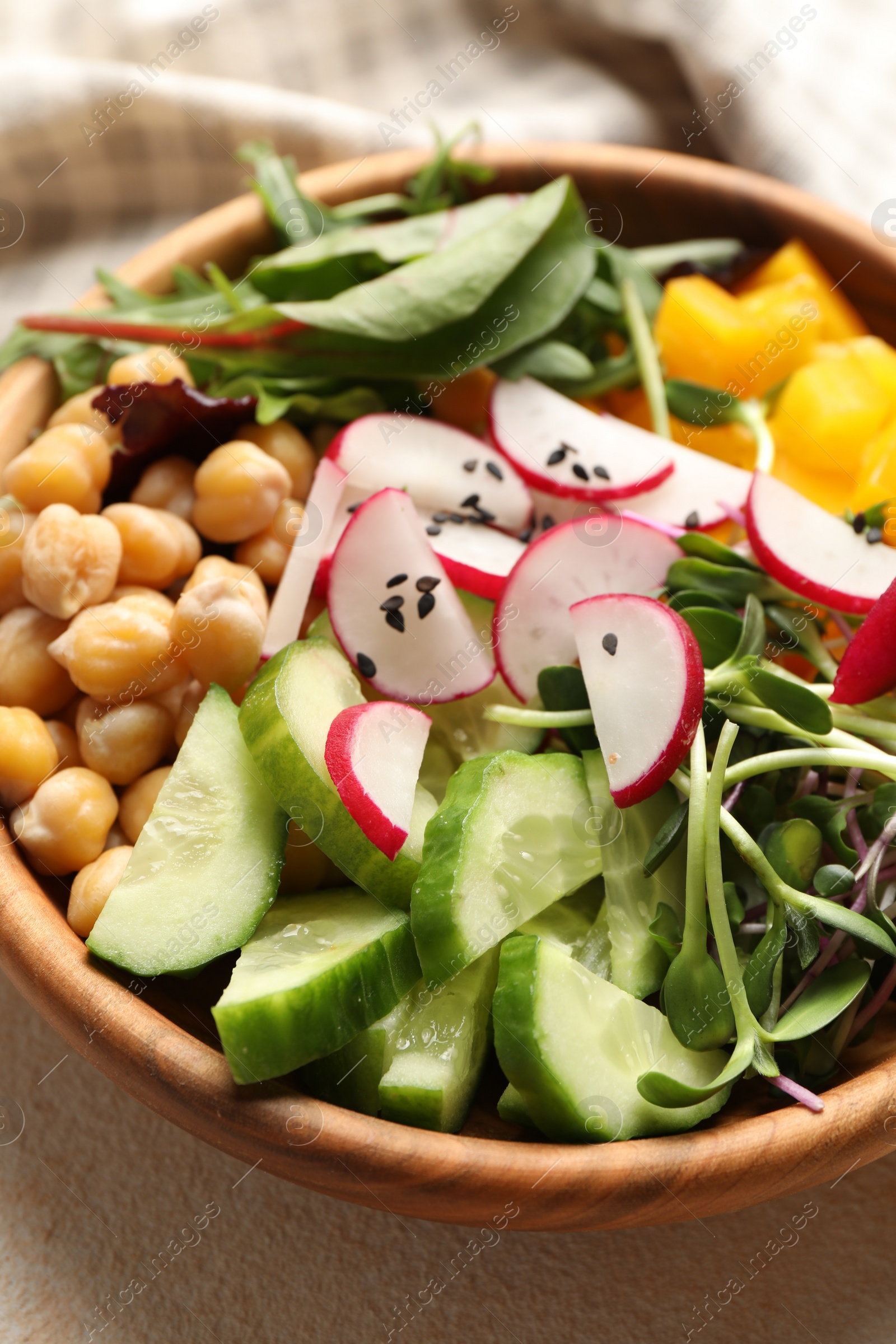 Photo of Delicious vegan bowl with cucumbers, chickpeas and radish on beige table, closeup