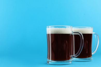 Photo of Delicious homemade kvass in glass mugs on light blue background. Space for text