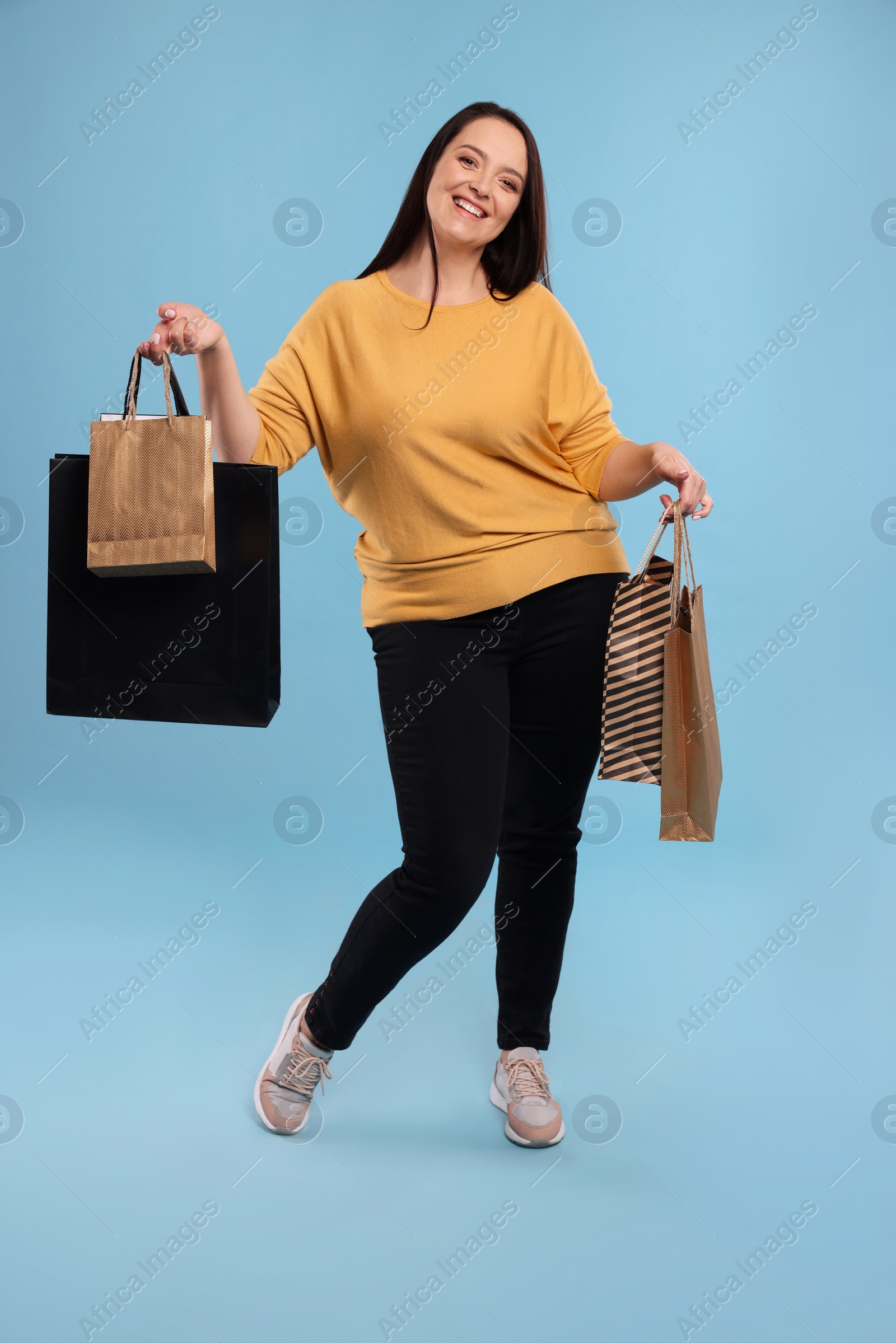 Photo of Beautiful overweight woman with shopping bags on turquoise background