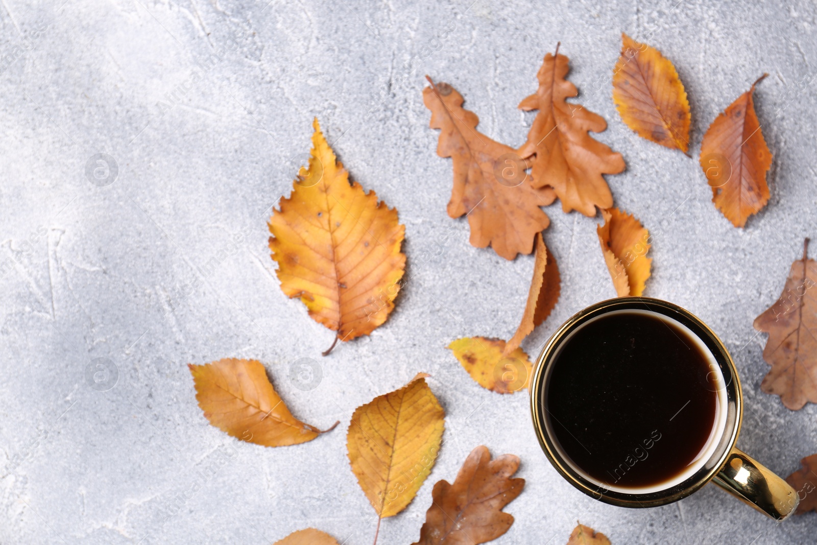 Photo of Flat lay composition with cup of hot drink and autumn leaves on light grey textured table. Space for text