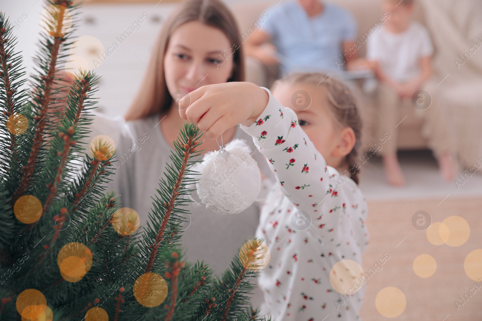 Photo of Mother with daughter decorating Christmas tree together at home, focus on hand