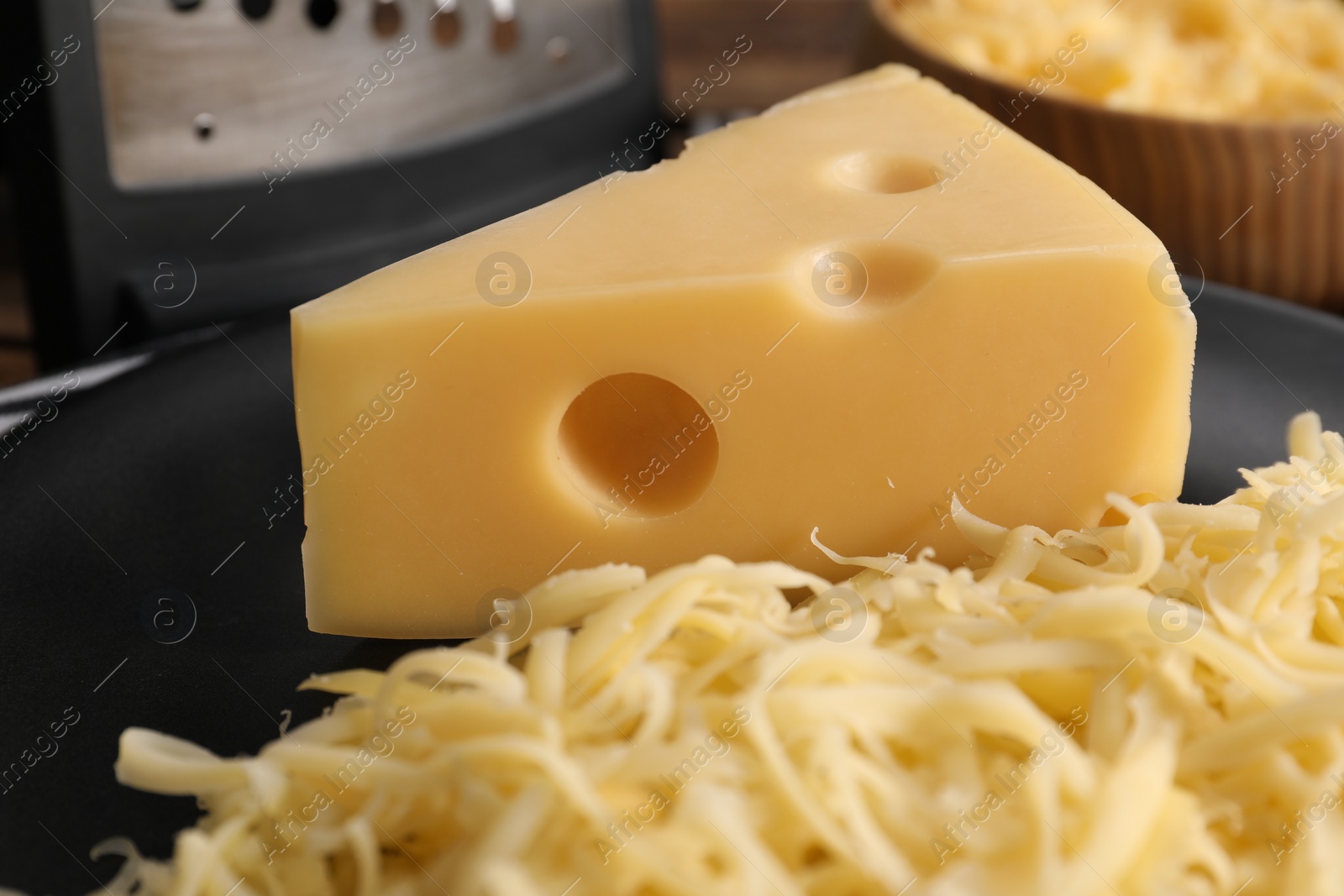 Photo of Grated and whole piece of cheese on plate, closeup