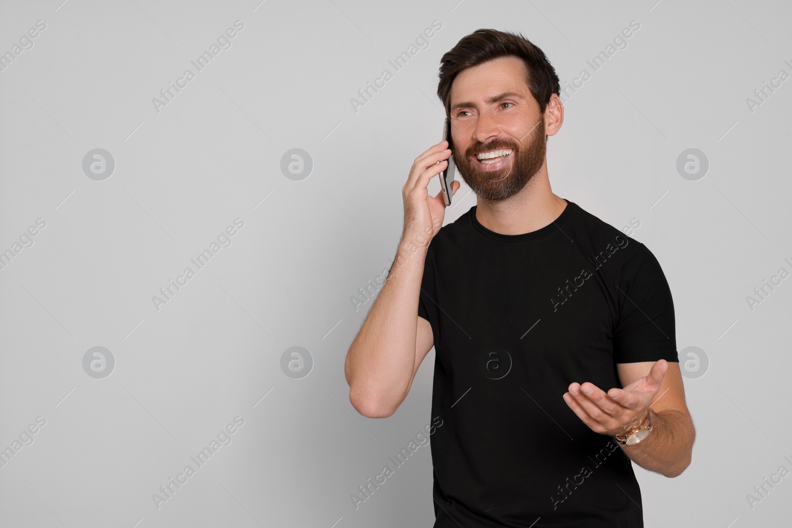Photo of Happy man talking on phone against light background. Space for text