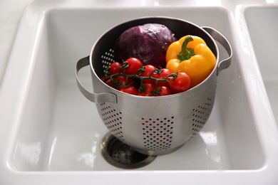 Photo of Colander pot with fresh vegetables in kitchen sink