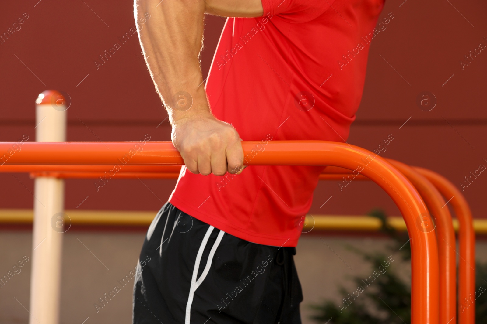Photo of Man training on parallel bars at outdoor gym, closeup