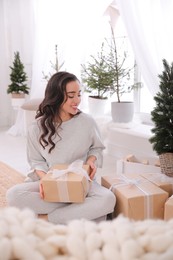 Photo of Woman with gift boxes on floor at home