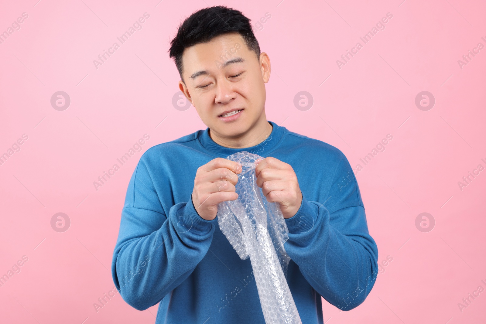 Photo of Asian man with bubble wrap on pink background