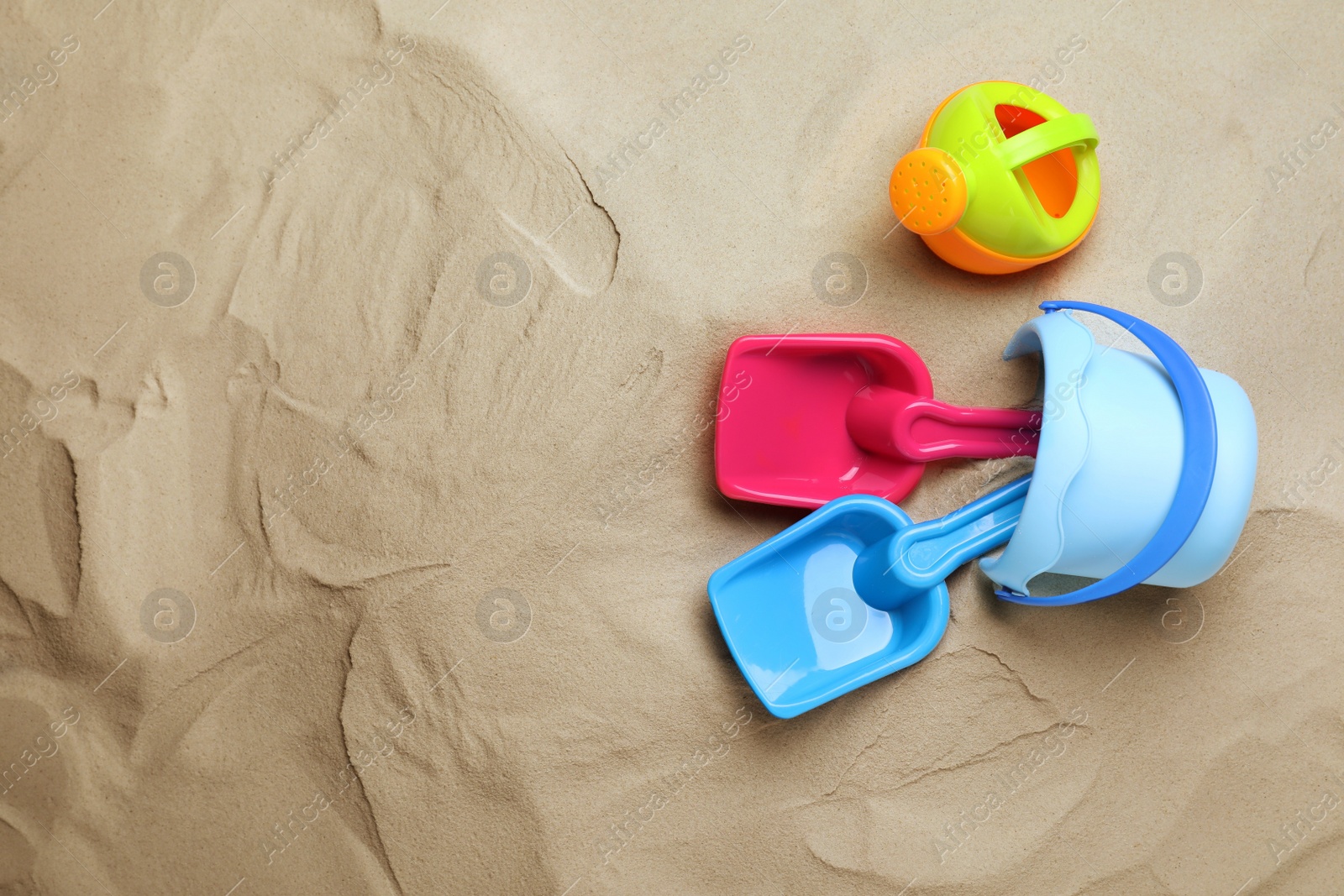 Photo of Plastic toy set with shovel on sand, flat lay