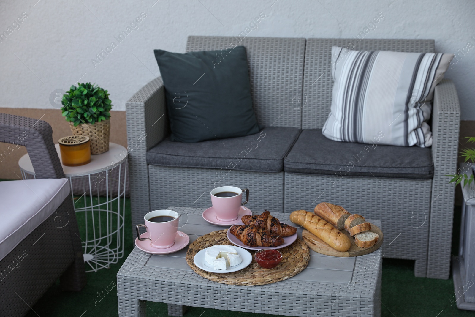 Photo of Outdoor breakfast with tea and croissants on rattan table on terrace