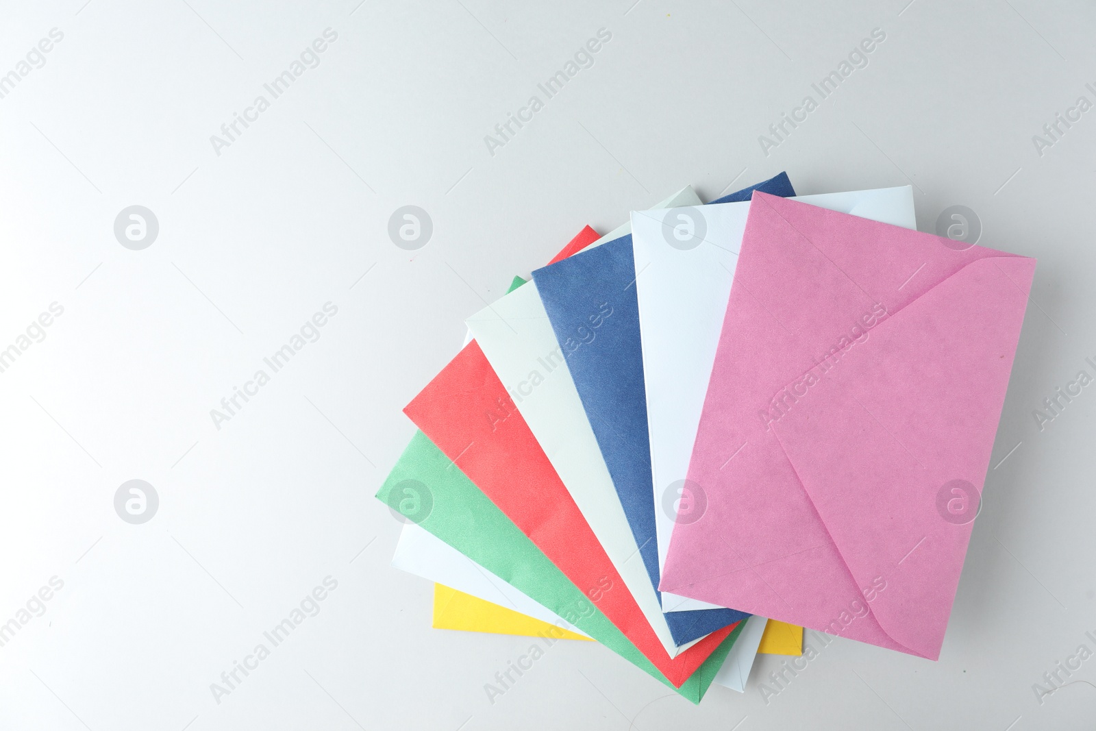 Photo of Colorful paper envelopes on light background, top view. Space for text