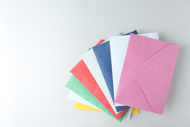Photo of Colorful paper envelopes on light background, top view. Space for text