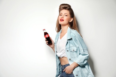 Photo of MYKOLAIV, UKRAINE - NOVEMBER 28, 2018: Young woman with bottle of Coca-Cola on white background