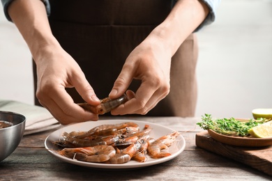 Photo of Woman preparing shrimps at table