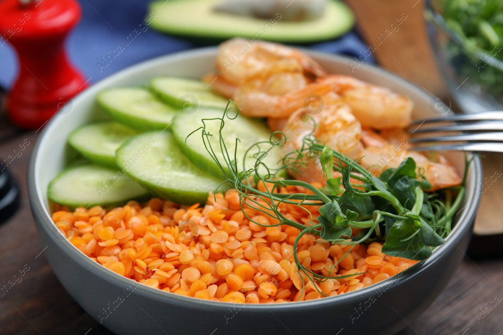 Photo of Delicious lentil bowl with shrimps and cucumber on wooden table, closeup