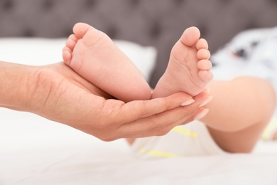 Photo of Mother holding her baby's feet on bed, closeup