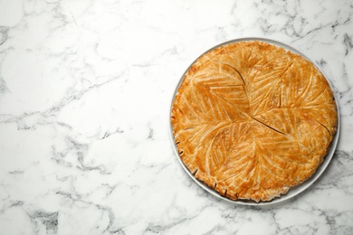 Photo of Traditional galette des rois on white marble table, top view. Space for text