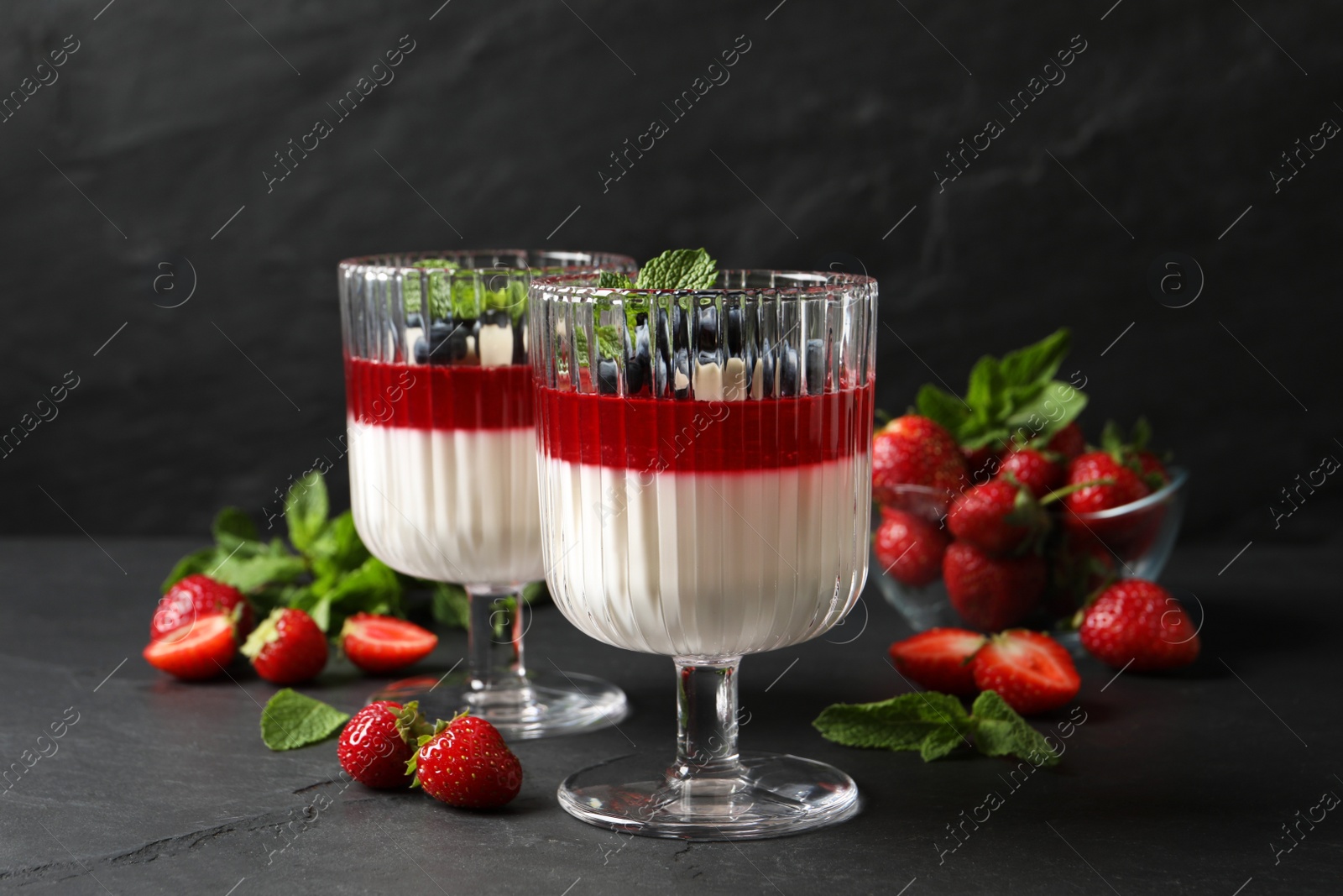 Photo of Delicious panna cotta with fruit coulis and fresh berries on dark grey table