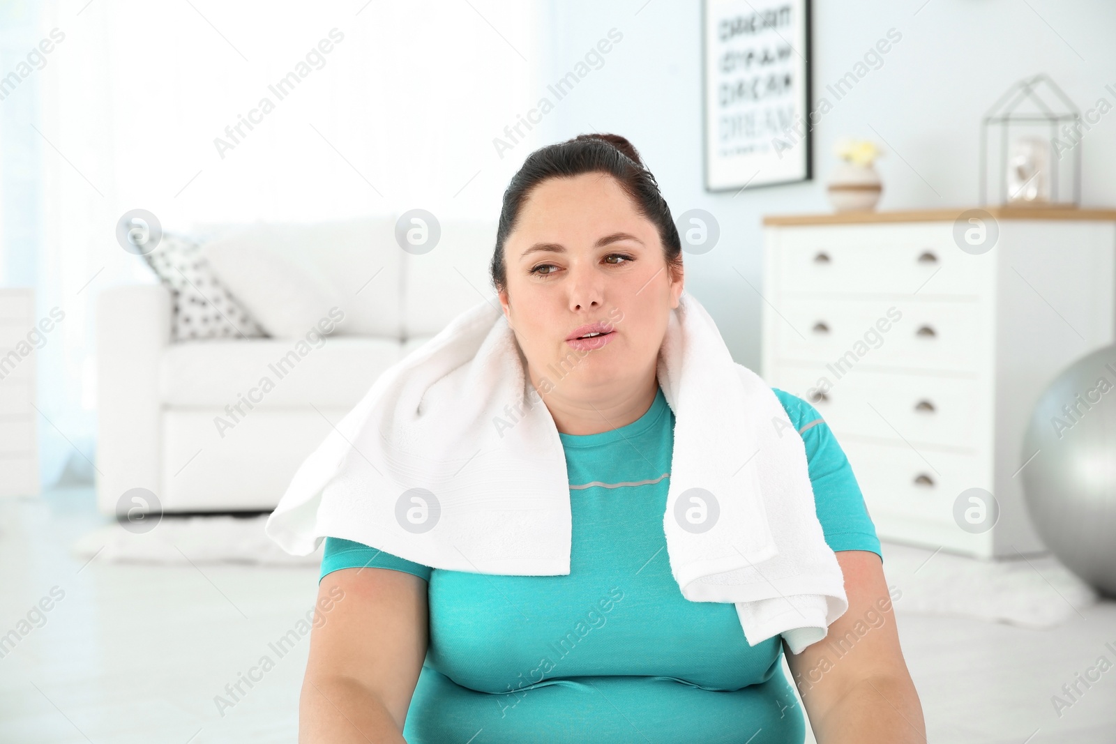 Photo of Tired overweight woman with towel at home