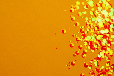 Photo of Shiny bright glitter on yellow background, flat lay. Space for text